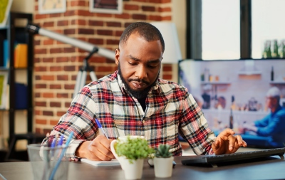 man writing up data on laptop